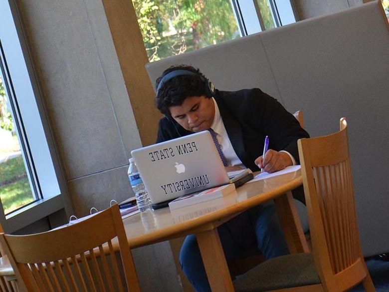 在图书馆使用笔记本电脑学习的学生